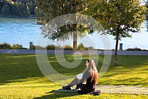 Young mother in black sitting on green lawn outside  and breastfeeding her baby on public