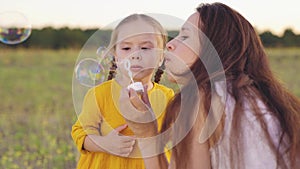 young mother blowing soap bubbles with little girl daughter. happy family. fun family bubble blowing game. child kid