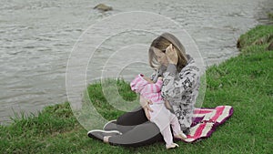 Young mother breast feeding her baby girl outdoors