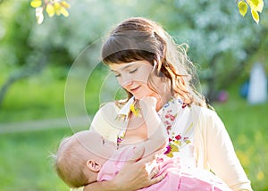 Young mother breast feeding her baby girl outdoors