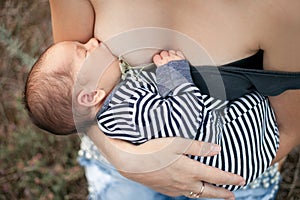 Young mother breastfeed newborn baby on walk. Close up.