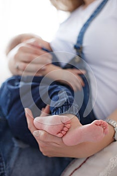 Young mother breastfeeding a child sitting on a bed in a bright bedroom