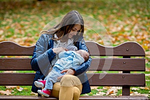 Young mother, breastfeeding her newborn baby boy outdoor in the