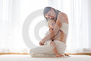 Young mother breastfeeding her toddler baby boy at home