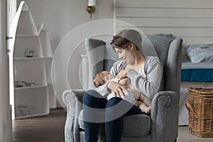 Young mother breastfeeding little newborn at home