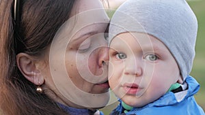 A young mother calms the baby in the park. To the son 2 years. Close-up