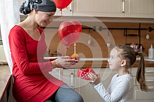 Young mother, cancer patient, and her cute daughter, celebrating birthday with balloons and presents.