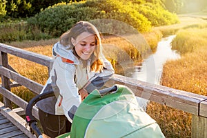 Young mother checking her baby in a stroller.