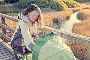 Young mother checking her baby in a stroller.