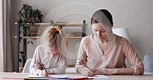 Young mother and child daughter drawing colored pencils together