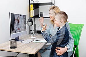 Young mother and child enjoying digital era, having online telemedicine consultation with remote doctor by professional