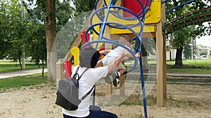 A young mother and child are playing on the playground on a sunny summer day. Happy family resting with baby outdoors.