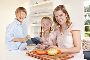 Young mother with children peeling vegetables