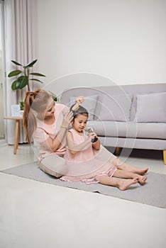 A young mother combing a hair little girl