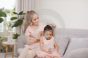 A young mother combing a hair little girl