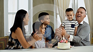 Young mother come in with birthday cake to little boy