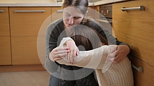 Young mother comforting and calming her daughter crying on floor at kitchen. Concept of domestic violence and family