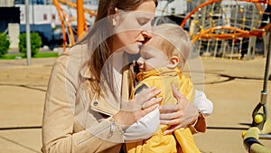 Young mother consoling and hugging her upset baby boy on playground. Children playing outdoor, kids outside, summer holiday and