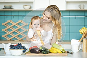 Young mother is cooking and playing with her baby daughter in a kitchen setting
