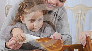 Young mother with cute girl makes a gingerbread house