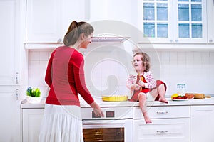 Young mother and daughter baking a pie together