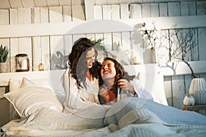 Young mother with daughter in bed huggings, lifestyle people at home concept