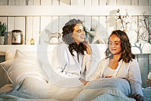 Young mother with daughter in bed huggings, lifestyle people at home concept