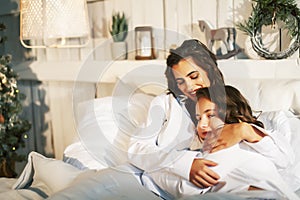 Young mother with daughter in bed huggings, lifestyle people at home concept