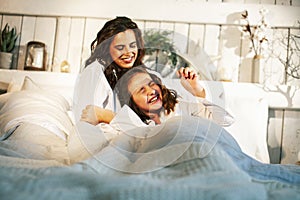 Young mother with daughter in bed huggings, lifestyle people at home concept