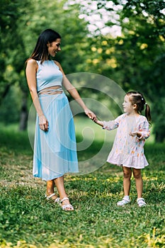 Young Mother and daughter playing and walking around the park on beautiful morning