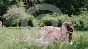 Young Mother And Daughter Reading Book Lying On Grass At Park