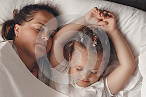 Young mother with daughter sleeping in bed