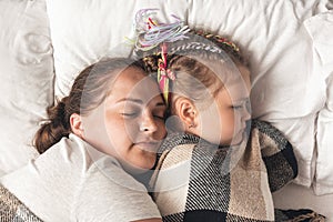 Young mother with daughter sleeping in bed