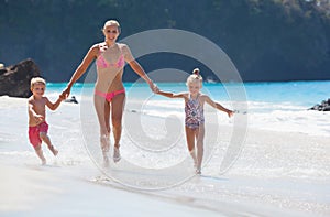 Young mother, daughter, son run by water pool along sea