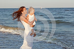 Young mother and daughter stand on the seashore