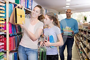 Young mother with daughter together in shop of school stationery