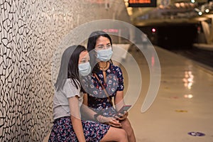 Young mother and daughter waiting for the metro wagon on the underground wearing face mask during pandemic of covid19
