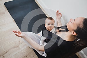 Young mother doing yoga with baby in ergo backpack