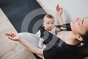 Young mother doing yoga with baby in ergo backpack