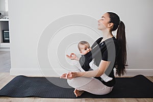 Young mother doing yoga with baby in ergo backpack