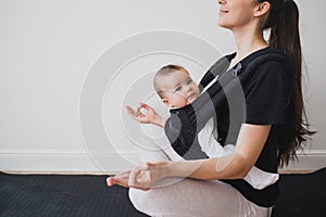 Young mother doing yoga with baby in ergo backpack