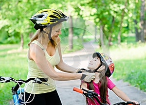 Young mother dresses her daughter's bicycle helmet