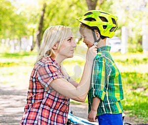 Young mother dresses her son bicycle helmet