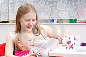 Young mother drink tea with adorable daughter