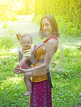 A young mother in Eastern dress, holding a small child in a Baby