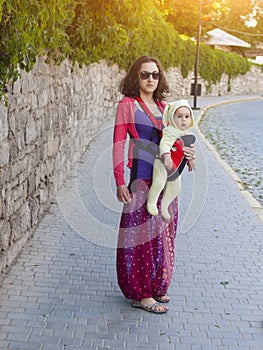 A young mother in Eastern dress, holding a small child in a Baby