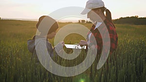 Young mother farmer teaches her daughter to work in a wheat field. Silhouette of a farmers family in a wheat field at