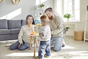 Young mother, father and their little daughter spend time at home in cozy children& x27;s room.