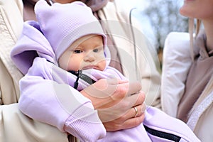 Young mother and father are walking with a newborn baby in the autumn park. The father holds the child in his arms