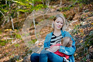 Young mother feeding a child by a lactation in a park.